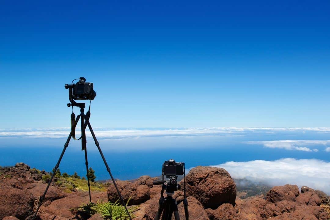 two nikon cameras on tripods at the edge of a cliff taking picture of the horizon