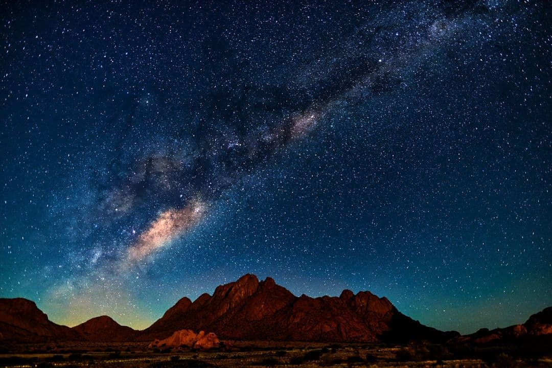 nightscape with a mountain range and a galaxy in the background