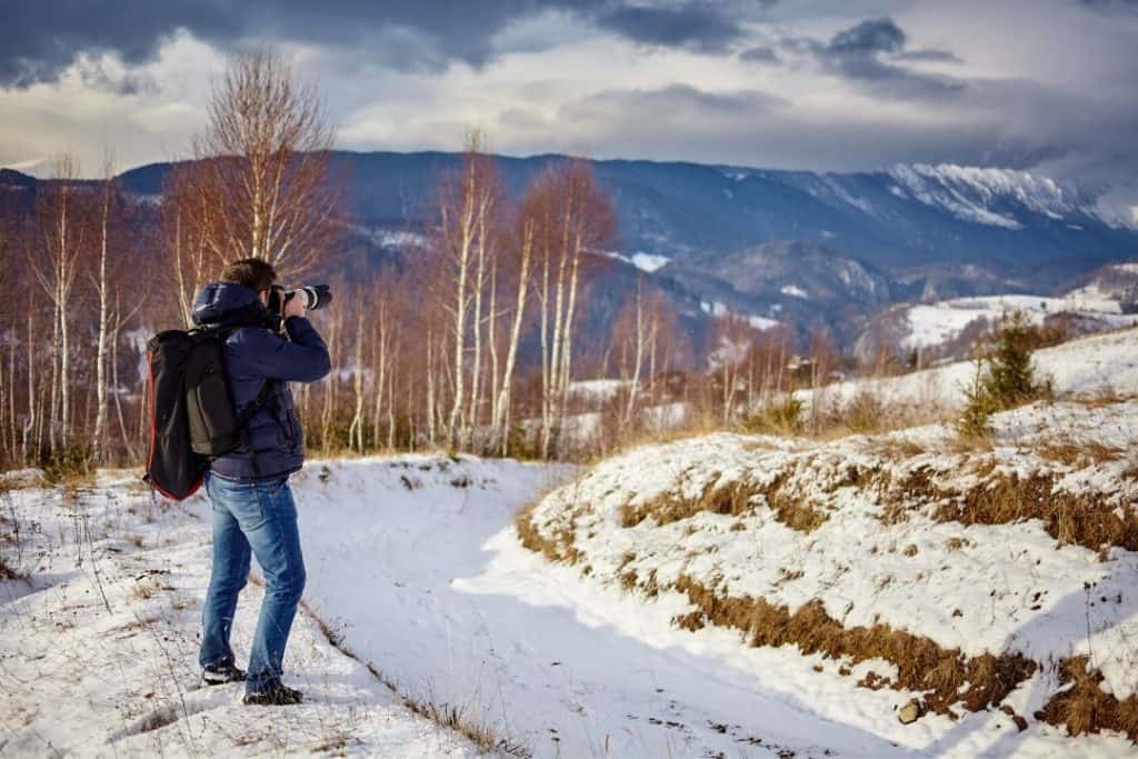 photographer taking a picture of a snowy mountain ridge